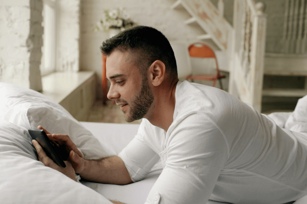 man using phone in bed morning